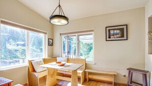 A bright room with large windows, wooden furniture, and a hanging light fixture. - 11 Acres of Adventure! Woodsy Mead Stay w/ Trails (Mead)