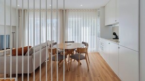 A modern kitchen with white cabinets, a dining table with chairs, and a sofa. - Simple Life II, Setúbal (Setúbal)