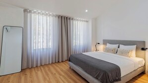 A modern bedroom with a large bed, a bedside table with a lamp, and sheer curtains. - Simple Life II, Setúbal (Setúbal)