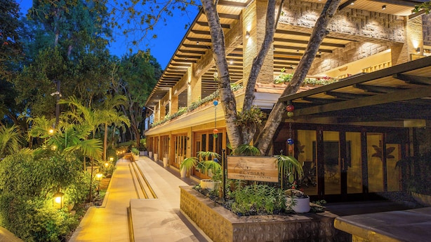 A hotel with a covered outdoor area, a sign for the Elysian Conference Centre, and a pathway lined with plants. - Pax Manor Muthaiga (Nairobi)