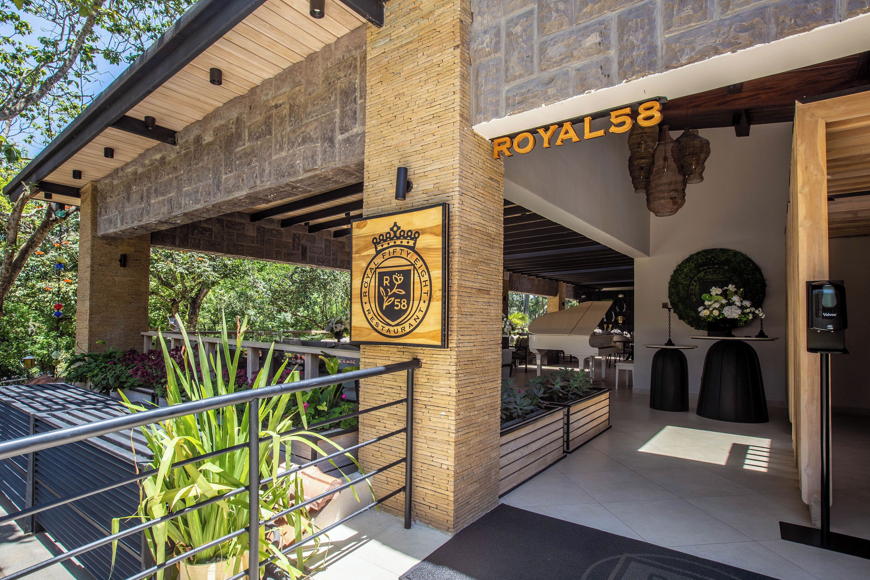 A covered outdoor area with a sign for Royal58, a brick pillar with a logo, and a metal railing.