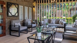 A modern living room with a stone wall, large windows, and a variety of seating options including sofas and chairs. - Pax Manor Muthaiga (Nairobi)