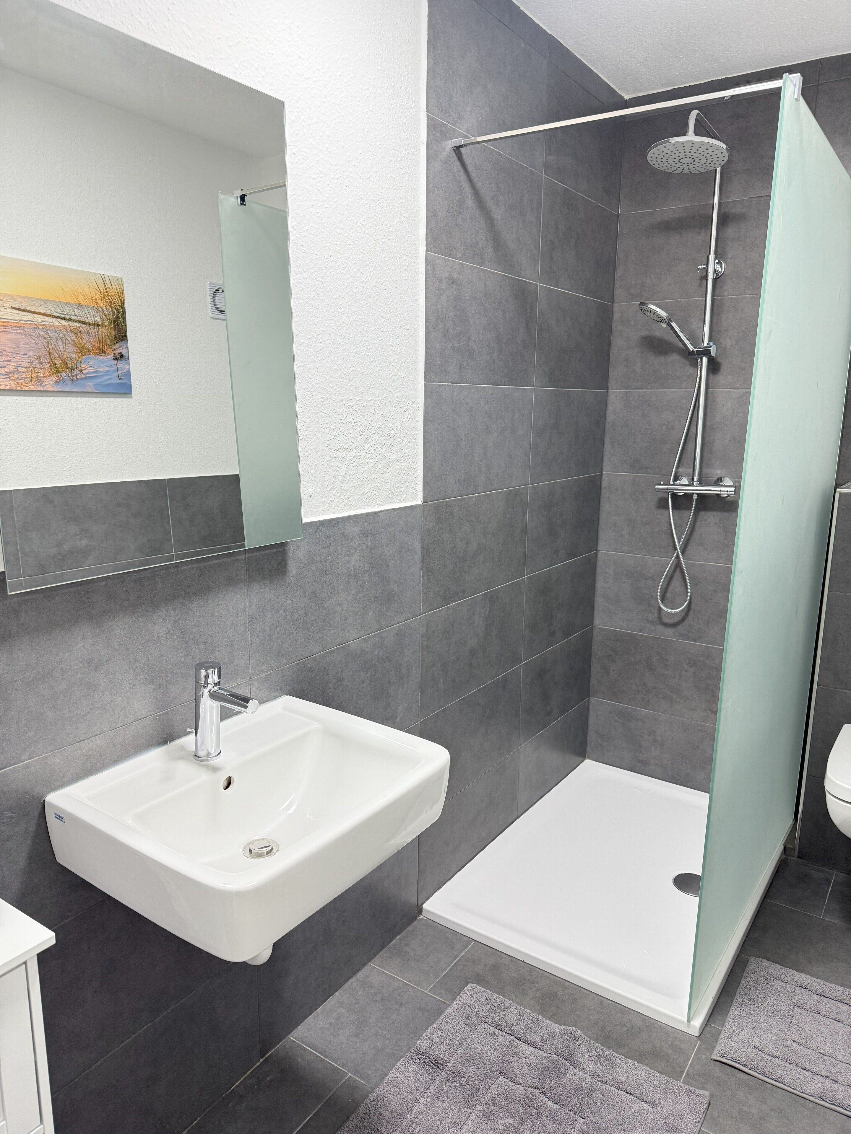 Un bagno moderno con doccia, lavandino e water.