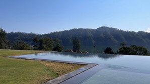 En swimmingpool med fri utsikt över ett skogbeklätt kullområde i bakgrunden.