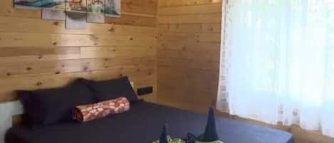 Un dormitorio de cabaña de madera con cama, ventilador de techo y una obra de arte en la pared.