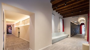 Un hall d’hôtel moderne avec un plafond en bois, un espace salon et un couloir orné d’une affiche.