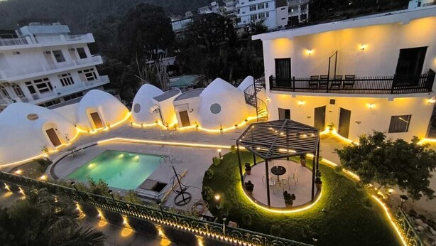 A modern hotel with a pool, outdoor seating, and a well-lit courtyard. - Shridhar Reesort (Rishikesh)