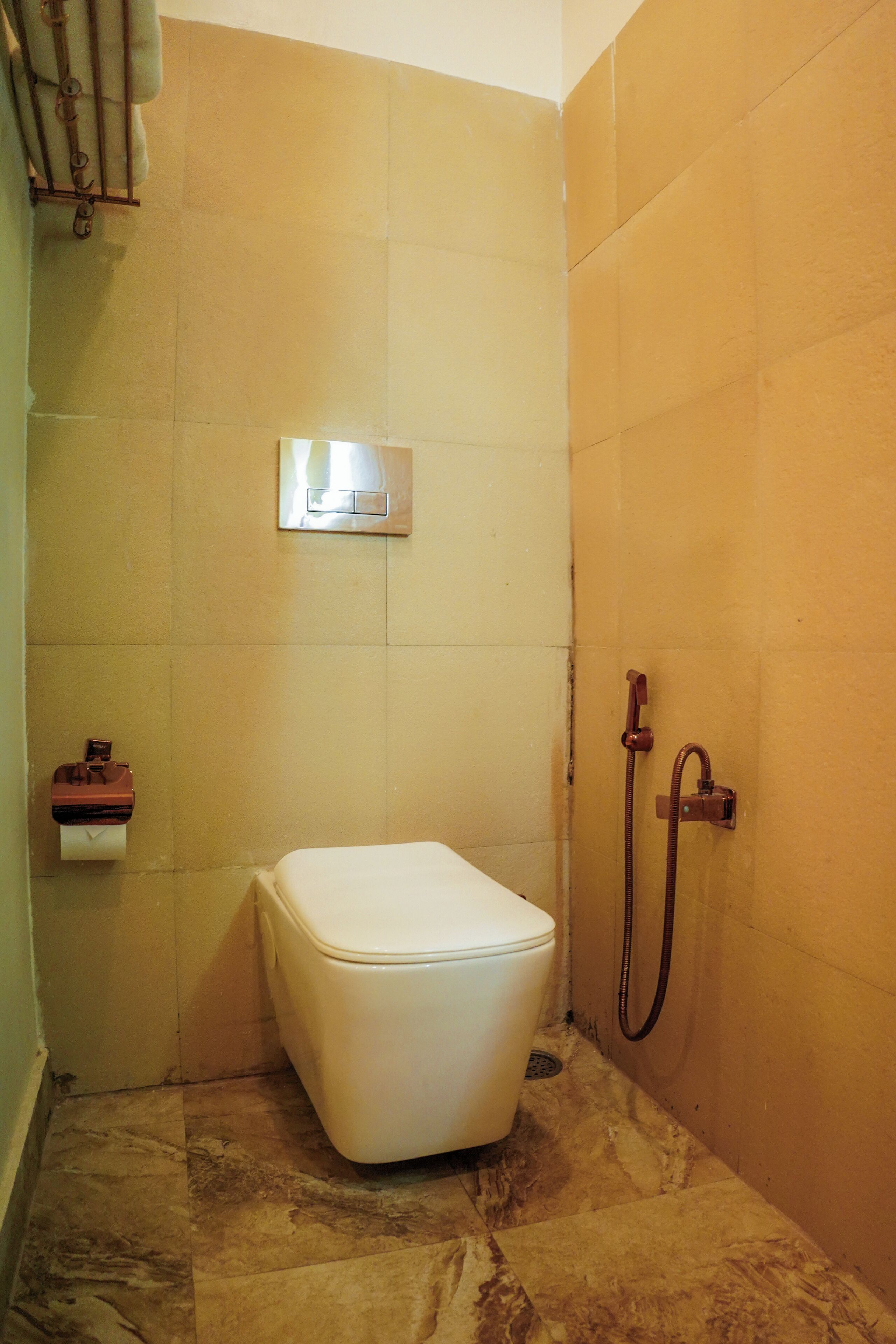 A bathroom with a toilet, a shower, and a towel rack.