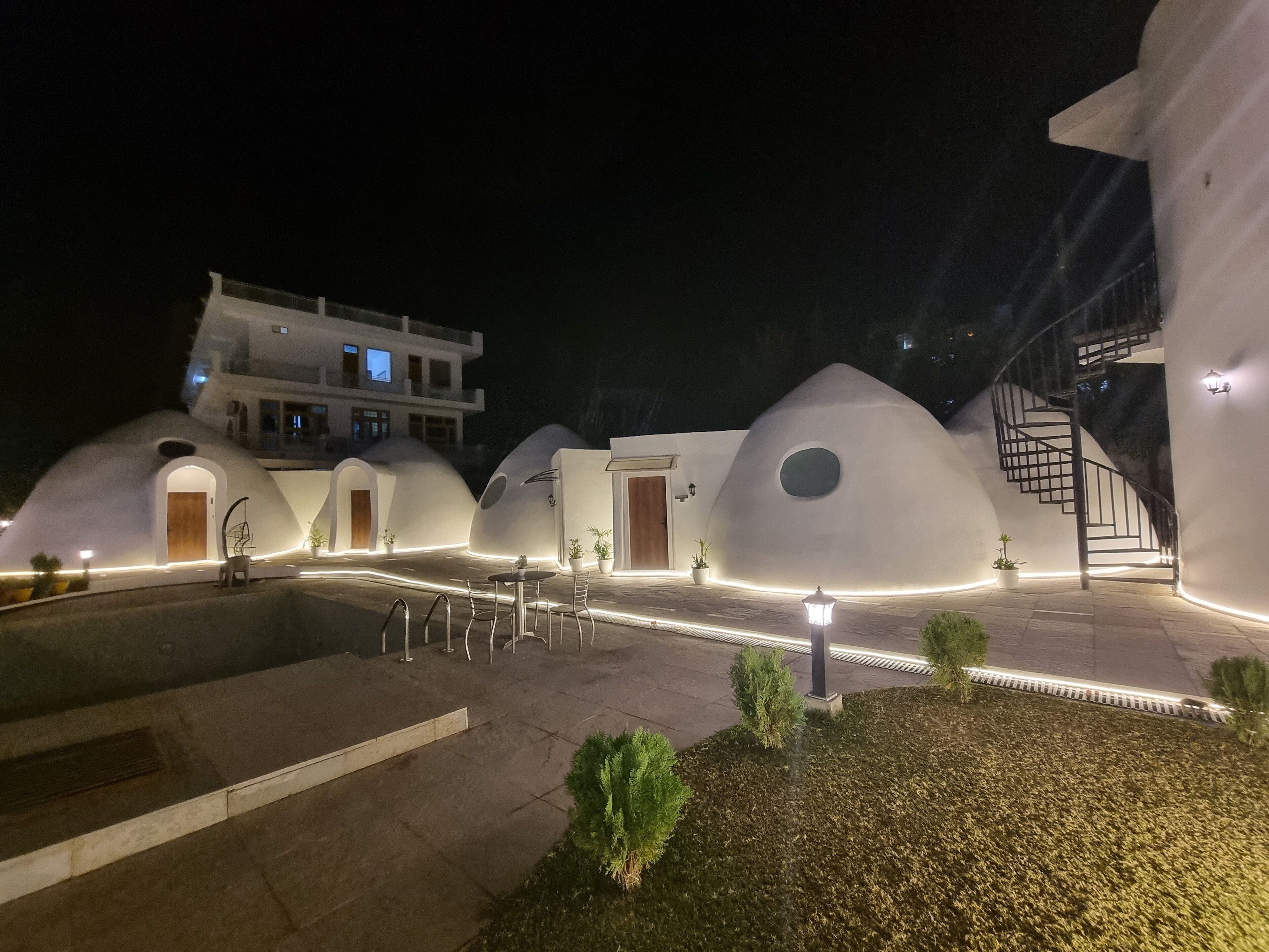 Un edificio moderno con estructuras geodésicas únicas, un patio central y una escalera que conduce a un nivel superior.