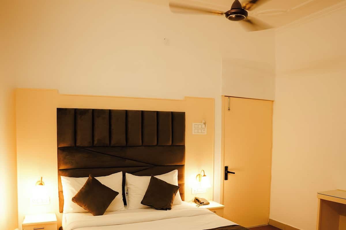 A bedroom with a large bed, a ceiling fan, and bedside lamps.