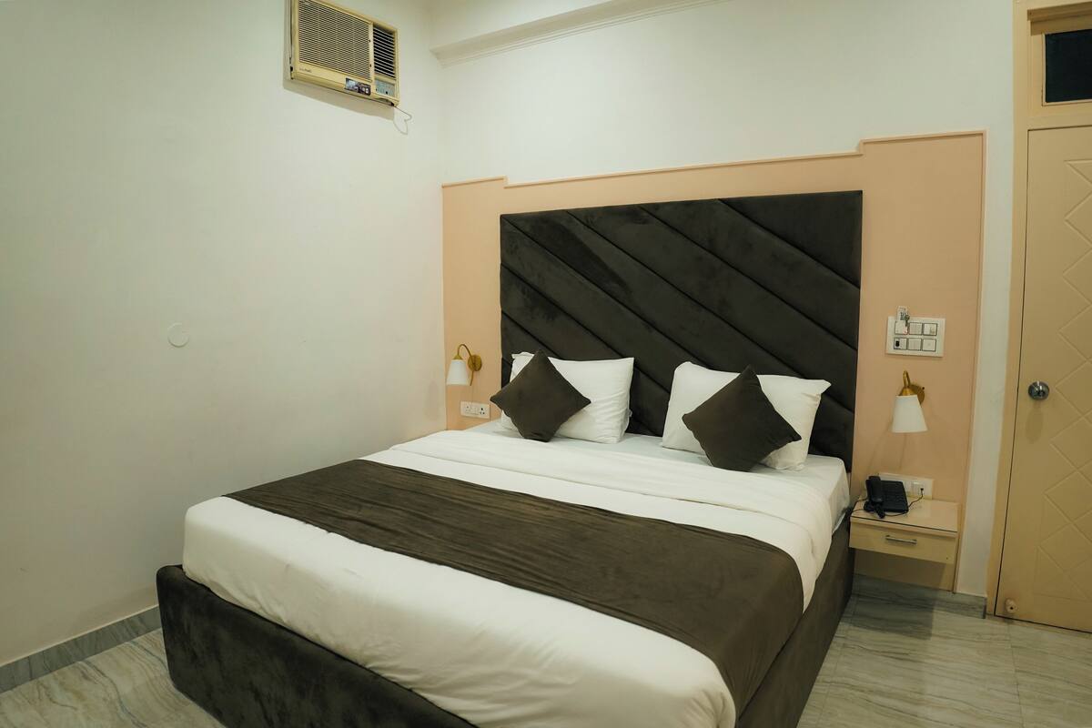 A neatly arranged bedroom with a bed, bedside lamps, a nightstand, and a door.