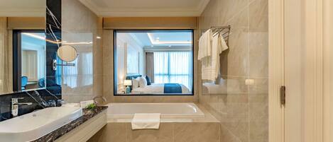 Un baño moderno con un espejo grande, una bañera y un lavamanos.