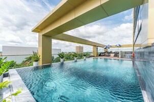 Una piscina al aire libre, sombrillas, sillones reclinables de piscina