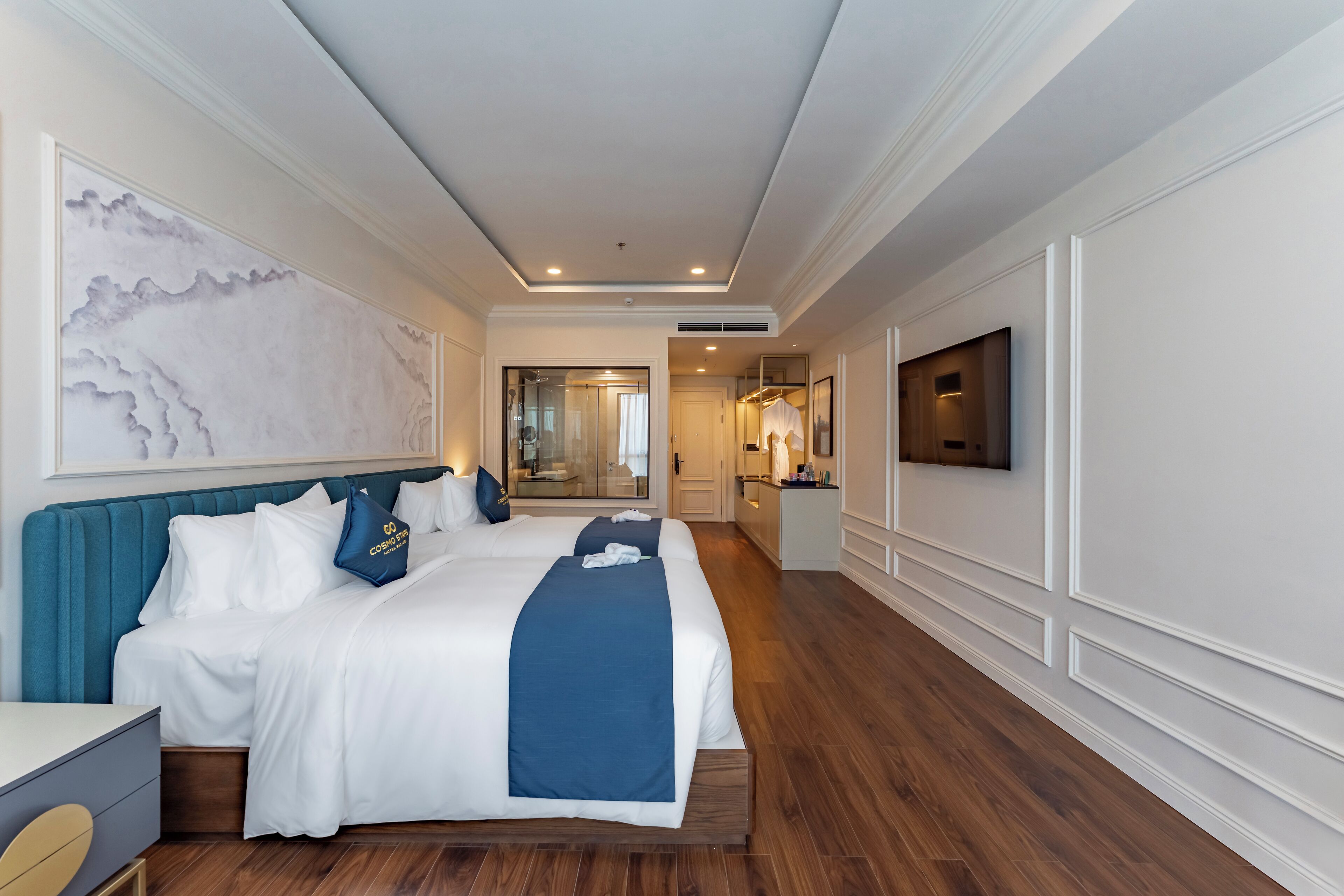 A hotel room with a large bed, a desk, a TV, and a bathroom visible through an open door.