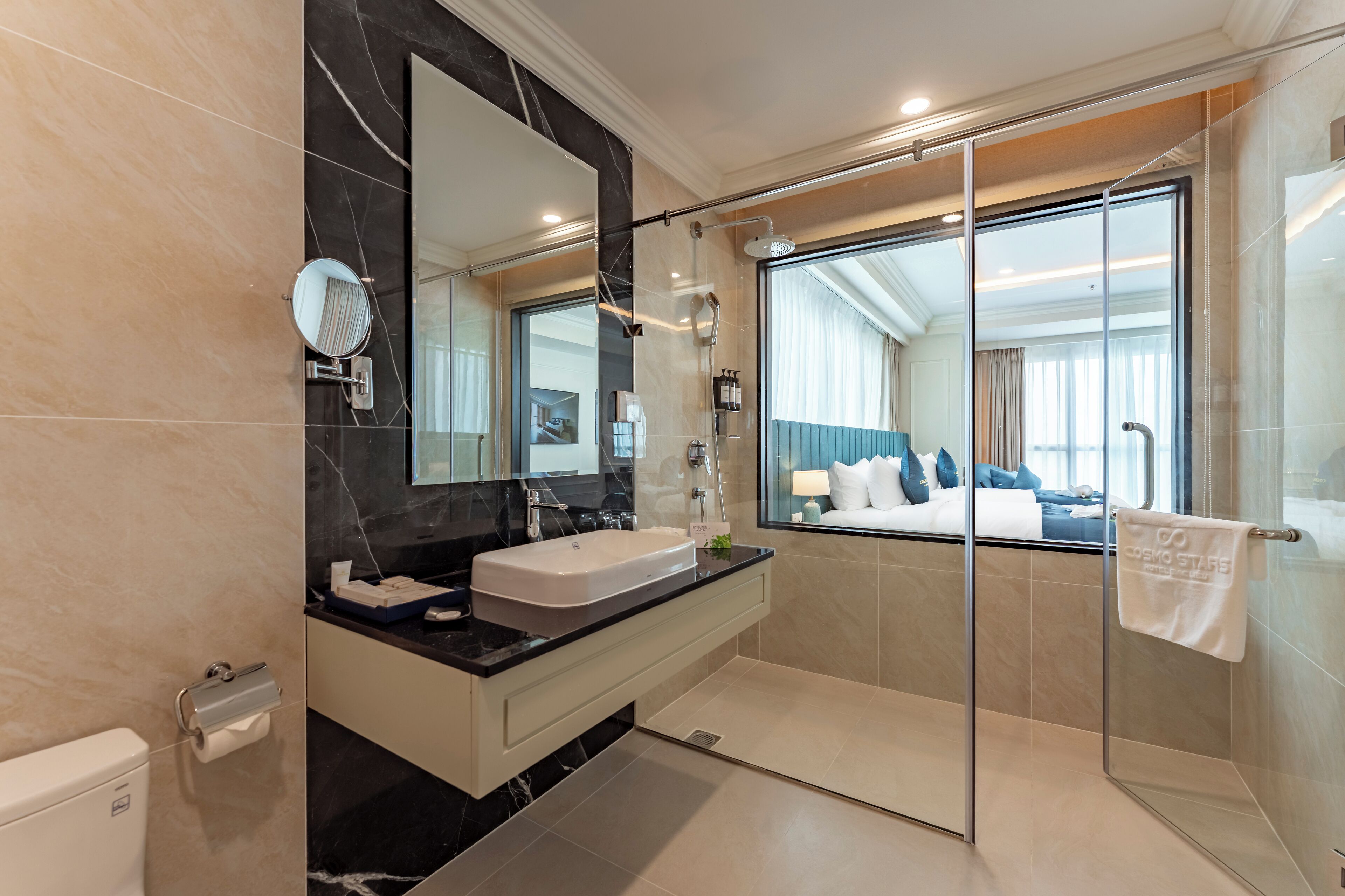 A modern bathroom with a large mirror, dual sinks, and a glass-enclosed shower.