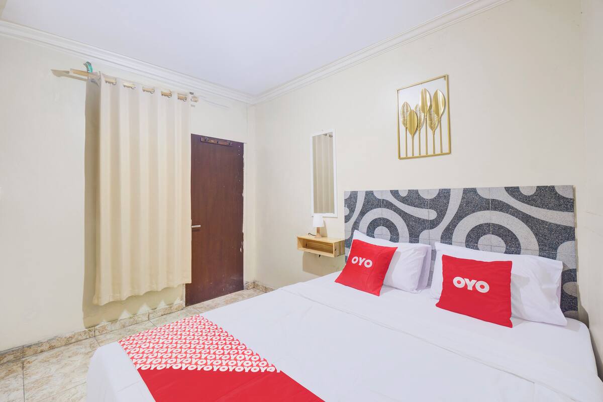 Une chambre d’hôtel avec un lit, un miroir, une porte et un mur orné d’un motif décoratif.