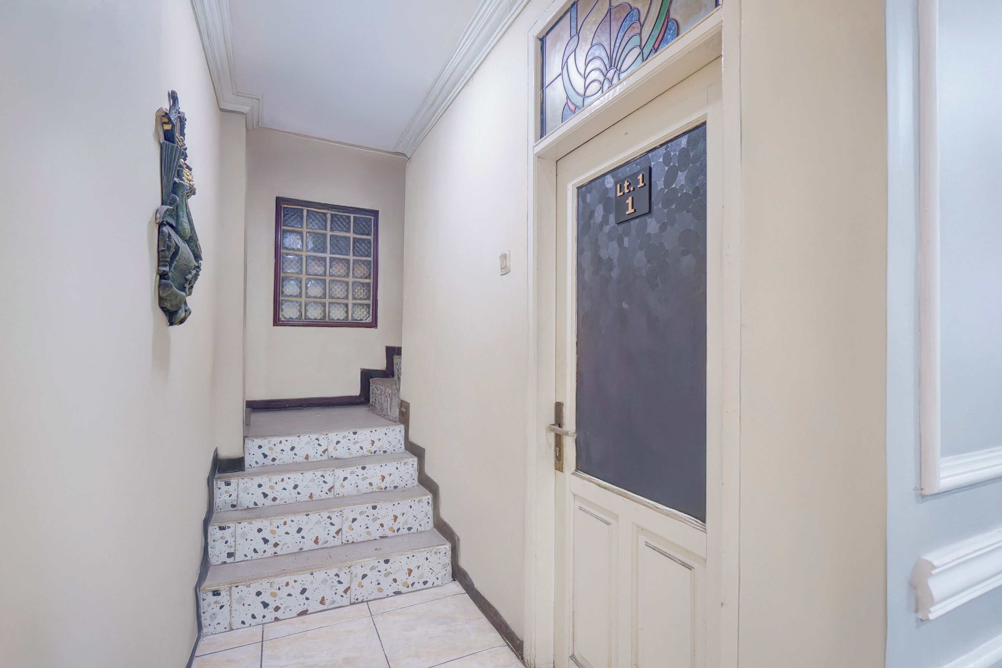 Una escalera con escalones de terrazo que lleva a una puerta marcada 'L.1'.