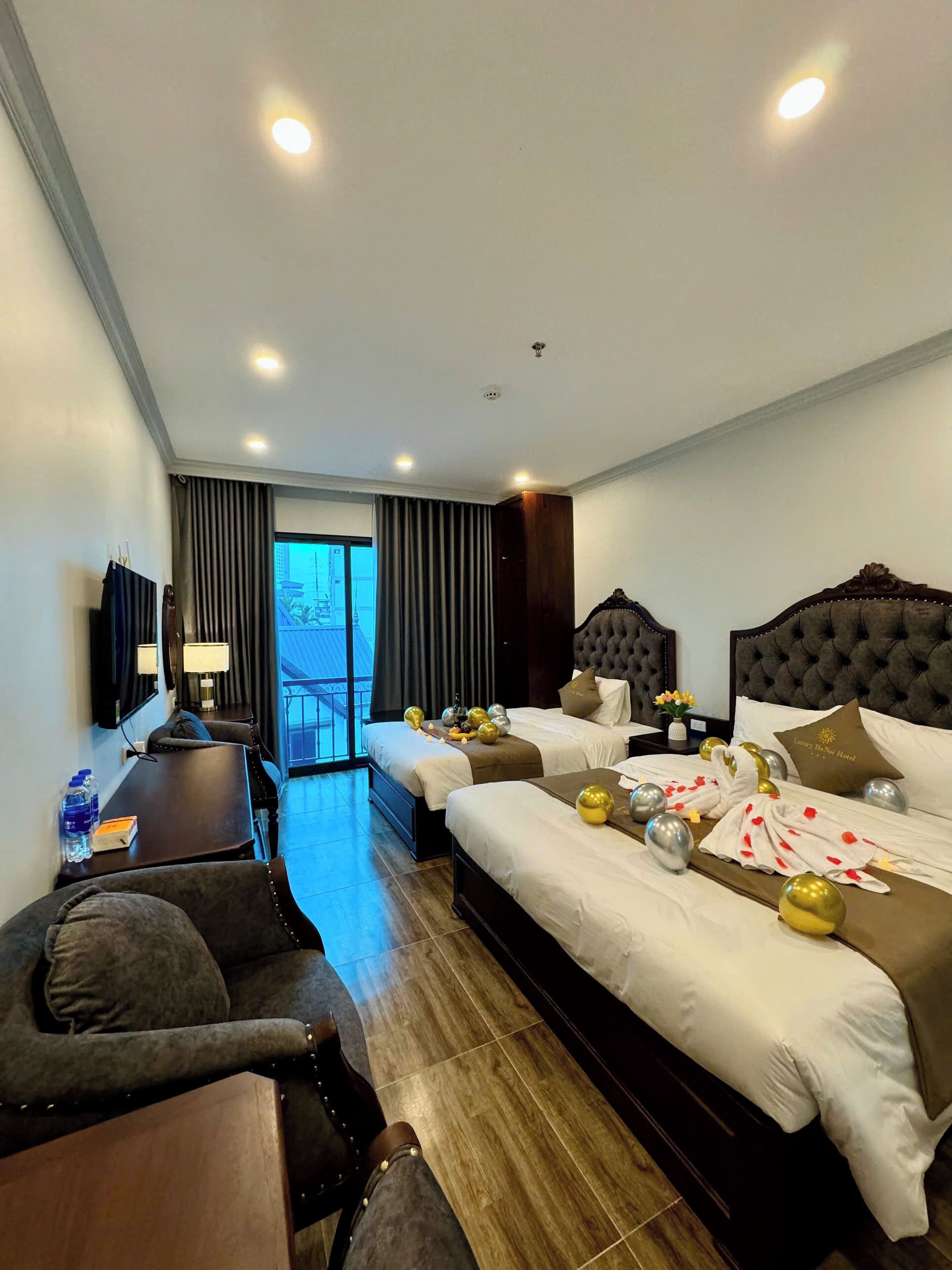 A hotel room with two beds, a desk, a chair, and a large window.