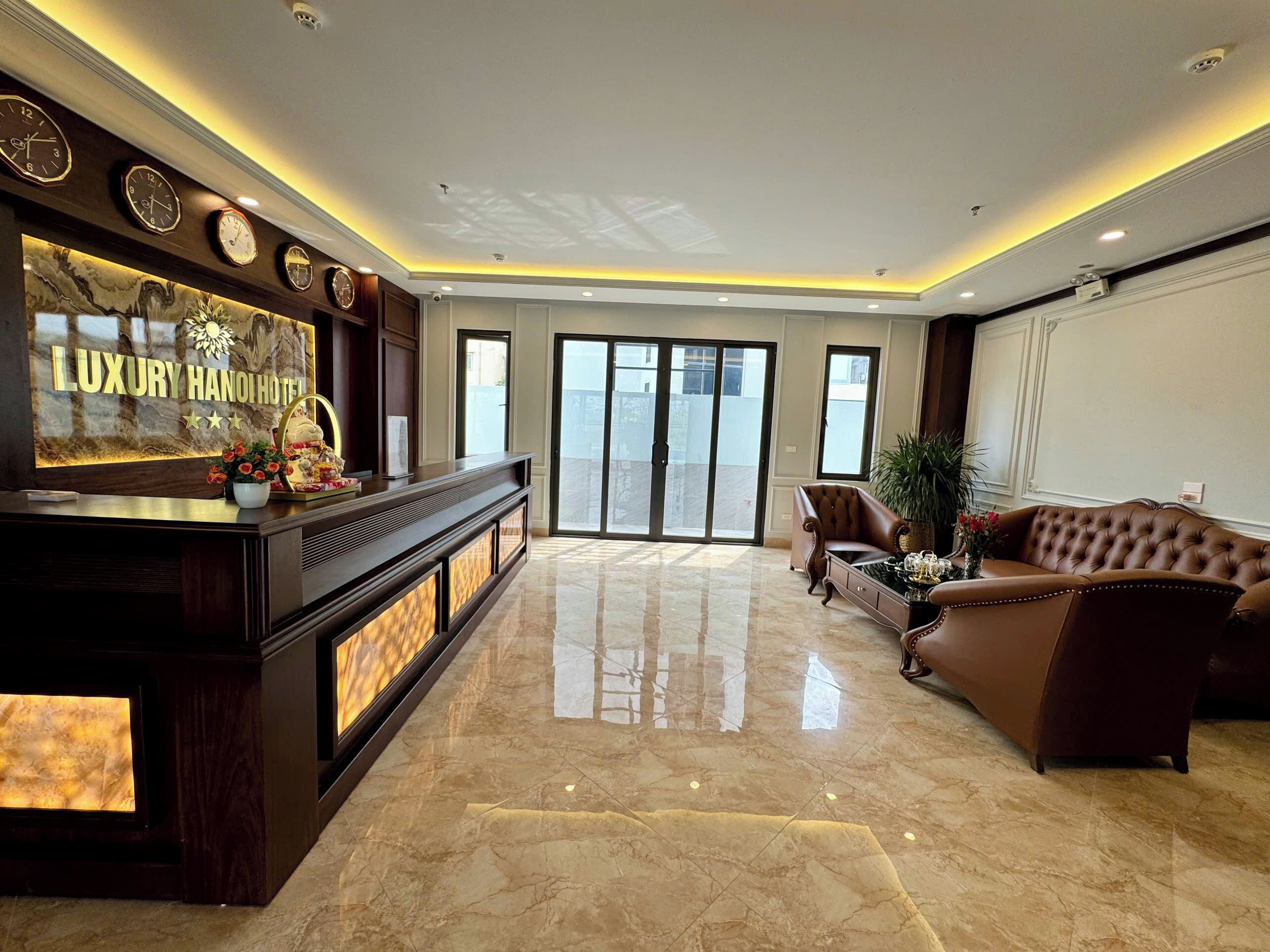 A spacious lobby with a marble floor, a reception desk with a digital display, and a leather sofa.