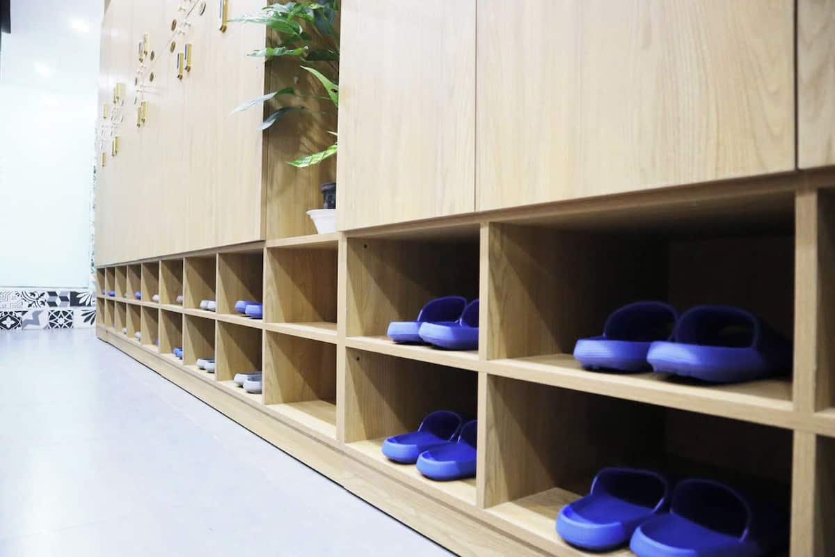 A row of wooden shoe shelves with blue shoes.