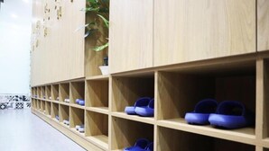 A row of wooden shoe shelves with blue shoes on them. - Amango Hostel (Ho Chi Minh City)