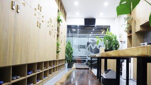 A modern interior with wooden lockers, a polished wooden bench, and potted plants. - Amango Hostel (Ho Chi Minh City)