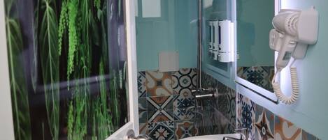 A bathroom with a white sink, a mirror, a hairdryer, and a shower.
