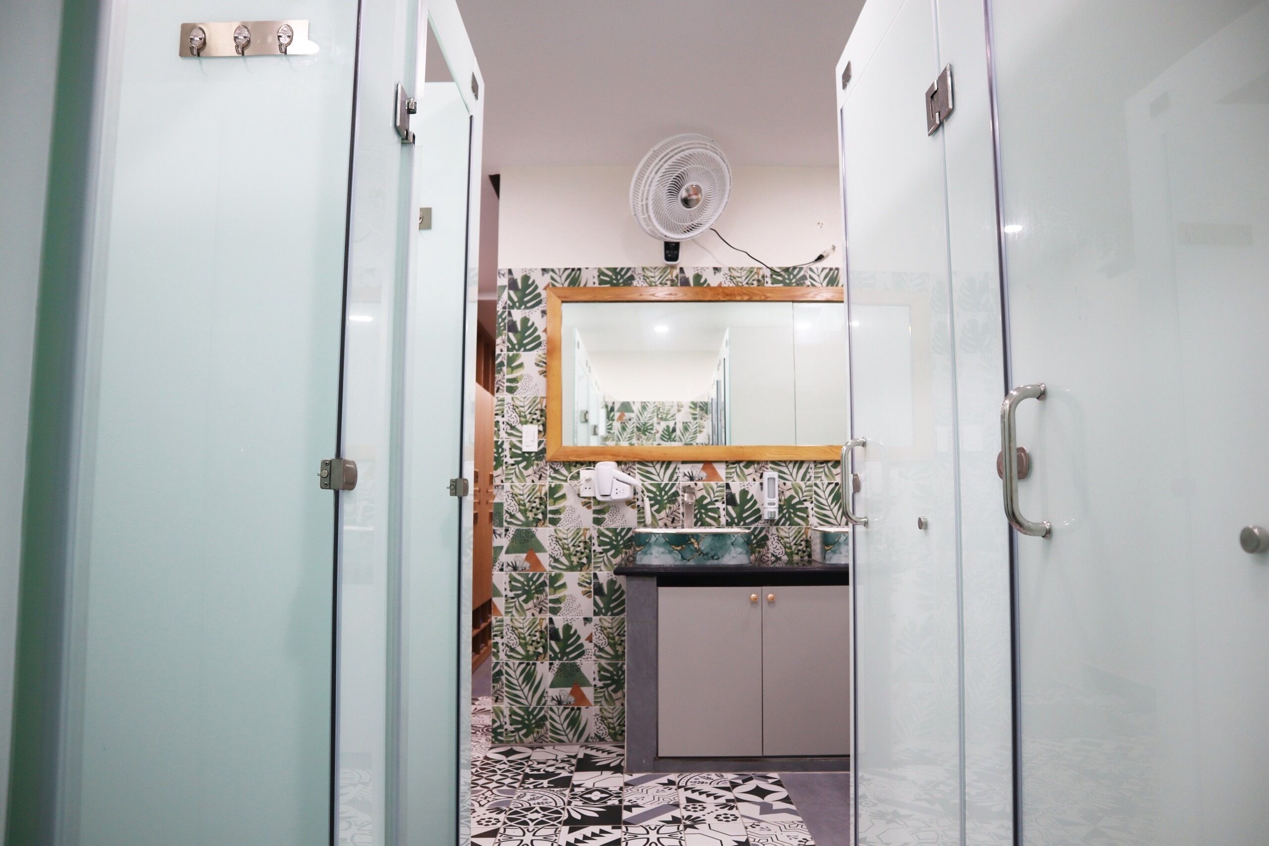 A narrow hallway with a mirrored wall, a small sink, and a fan on the ceiling.