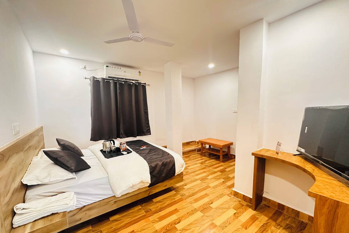 A hotel room with a bed, a desk, a television, and a ceiling fan.