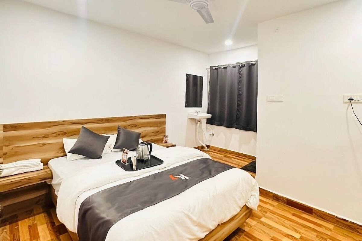A neatly arranged bedroom with a wooden bed, a ceiling fan, a bedside table, and a window with curtains.
