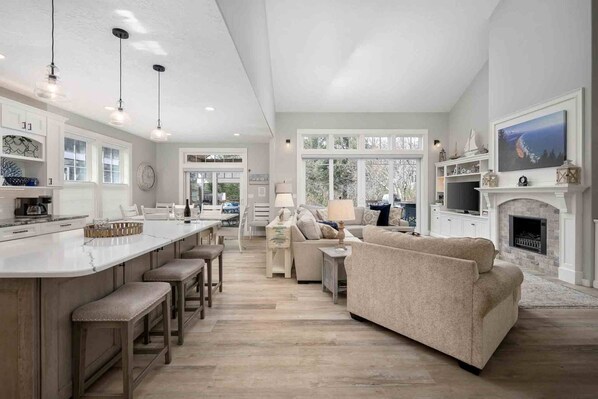 A spacious kitchen with a large island, a dining area with a sofa, and a living room with a fireplace.