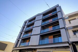 Un edificio de varios pisos con un diseño arquitectónico moderno, que cuenta con balcones y grandes ventanales.