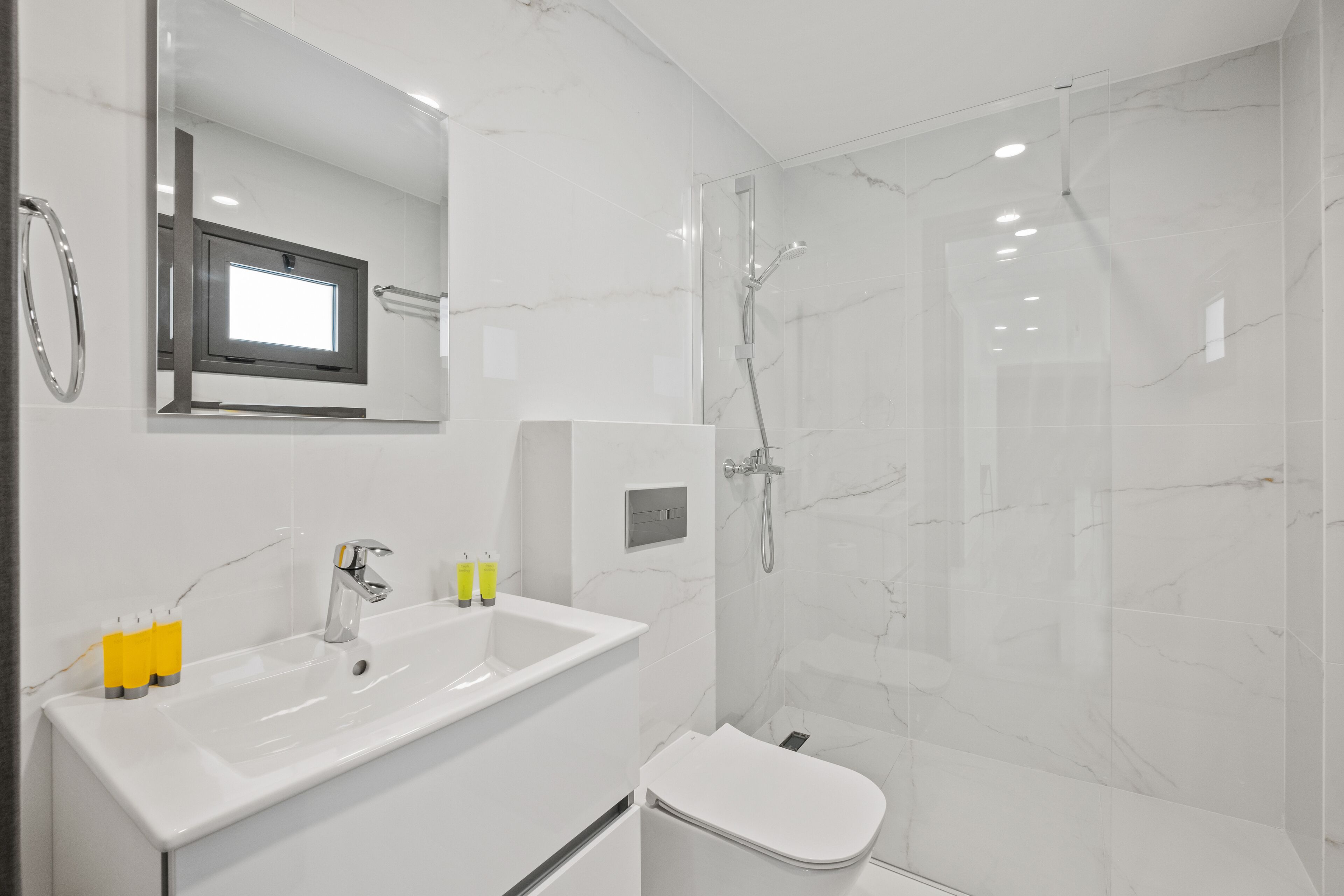A modern bathroom with a large mirror, two sinks, a toilet, and a shower enclosure.