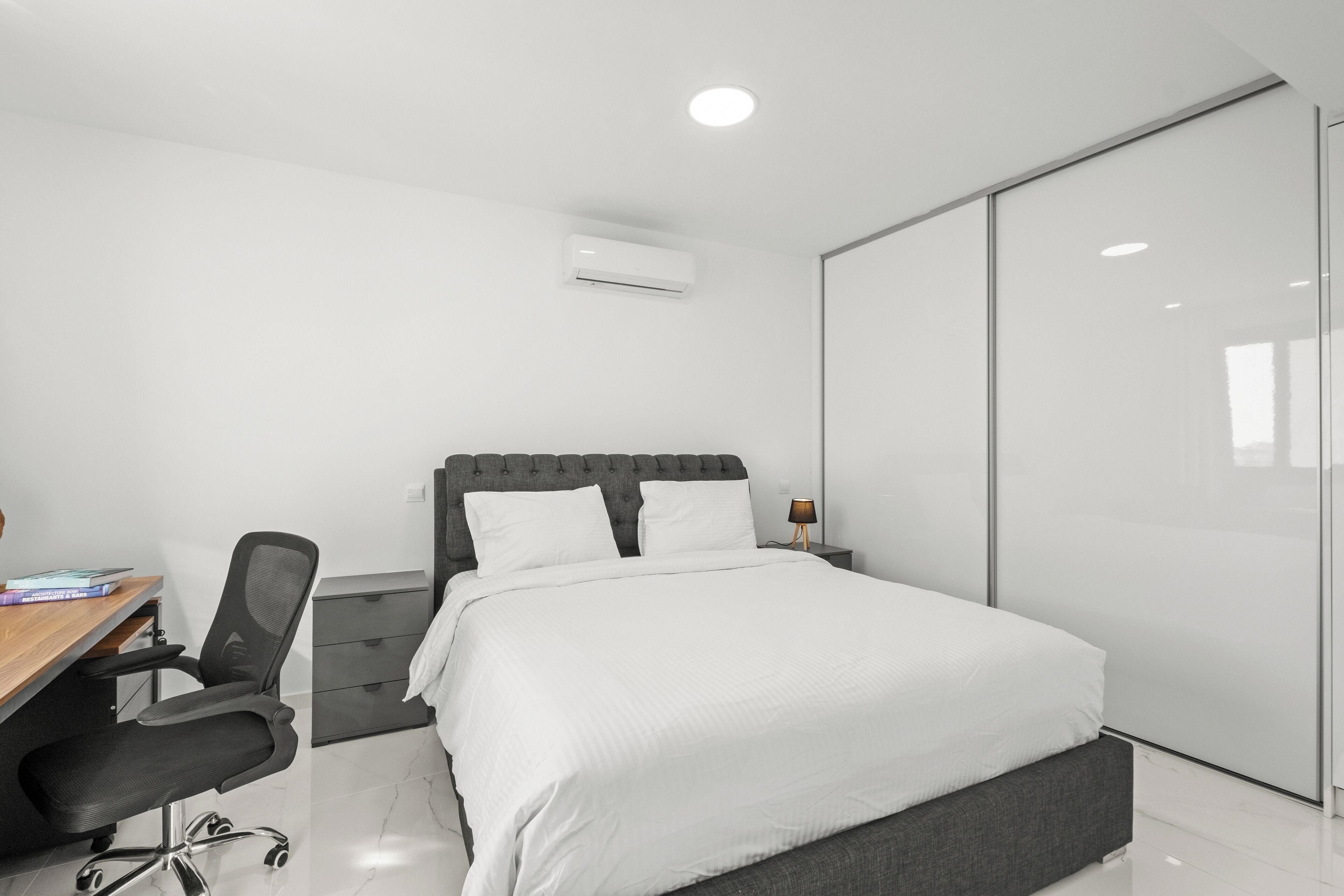 Un dormitorio moderno con cama, escritorio y silla.