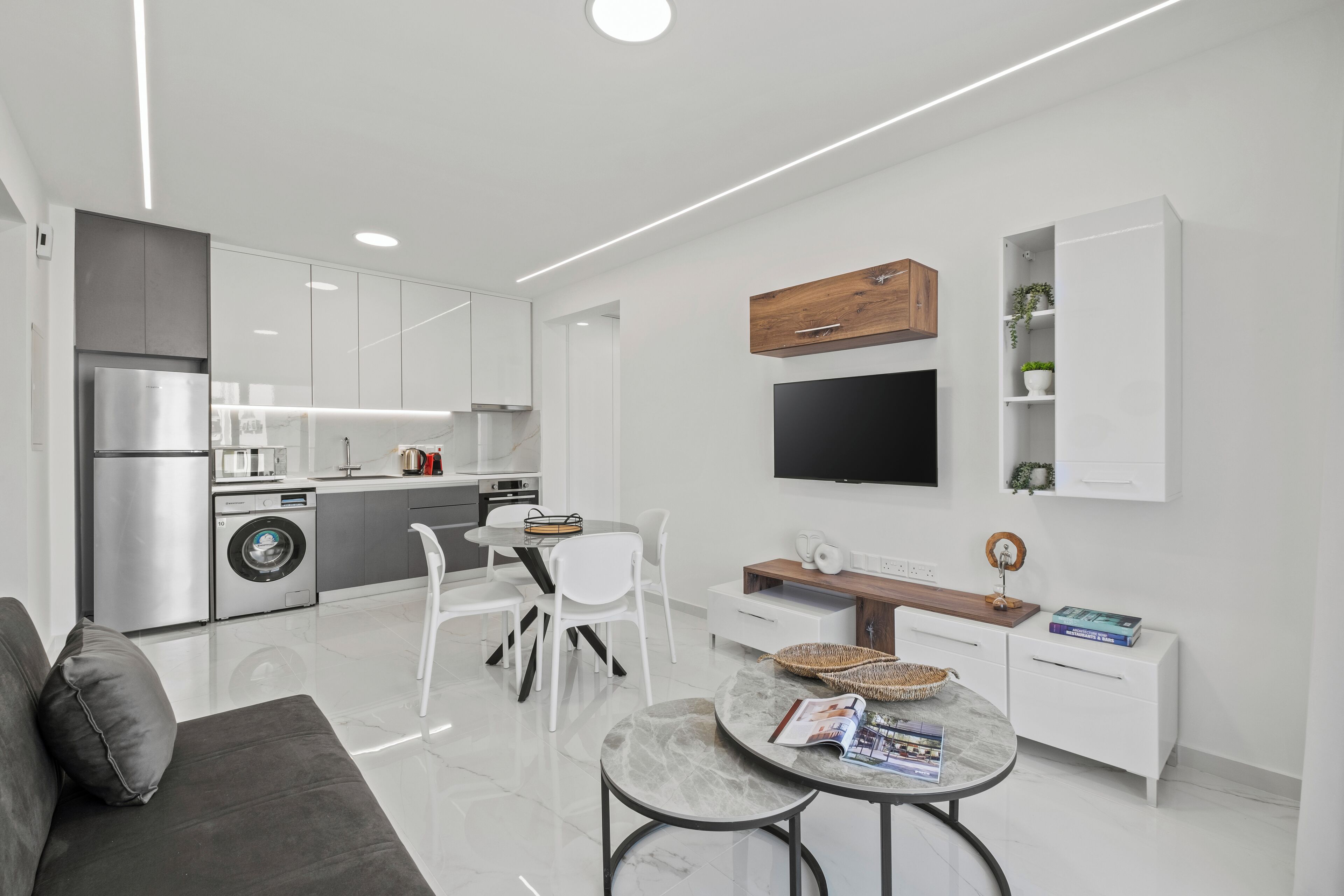 Una cocina moderna con armarios blancos, horno empotrado y refrigerador de acero inoxidable.