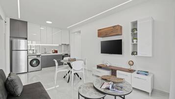 Una cocina moderna con armarios blancos, horno empotrado y refrigerador de acero inoxidable.