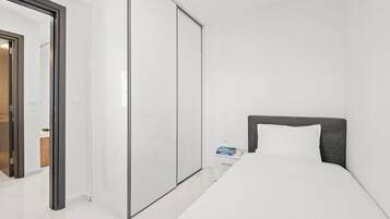 A modern hotel room with a large bed, a wardrobe, and a small bedside table.