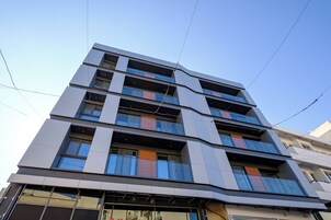 Un edificio de varios pisos con un diseño arquitectónico moderno, que cuenta con ventanas amplias y balcones.