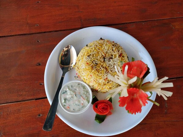 A plate of rice with a spoon and a small bowl of soup on a wooden table. - jay sambhoo pumdikot lodge (Pokhara)