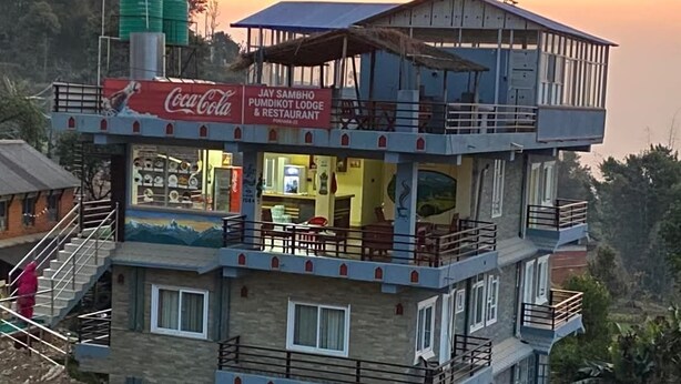 Un edificio a più piani con un cartello Coca-Cola, un ristorante e vista sul paesaggio circostante.
