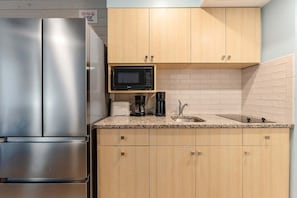 A kitchen with stainless steel appliances, wooden cabinets, a microwave, a coffee maker, and a sink.