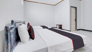 Een slaapkamer met een bed, nachtkastje en deur.