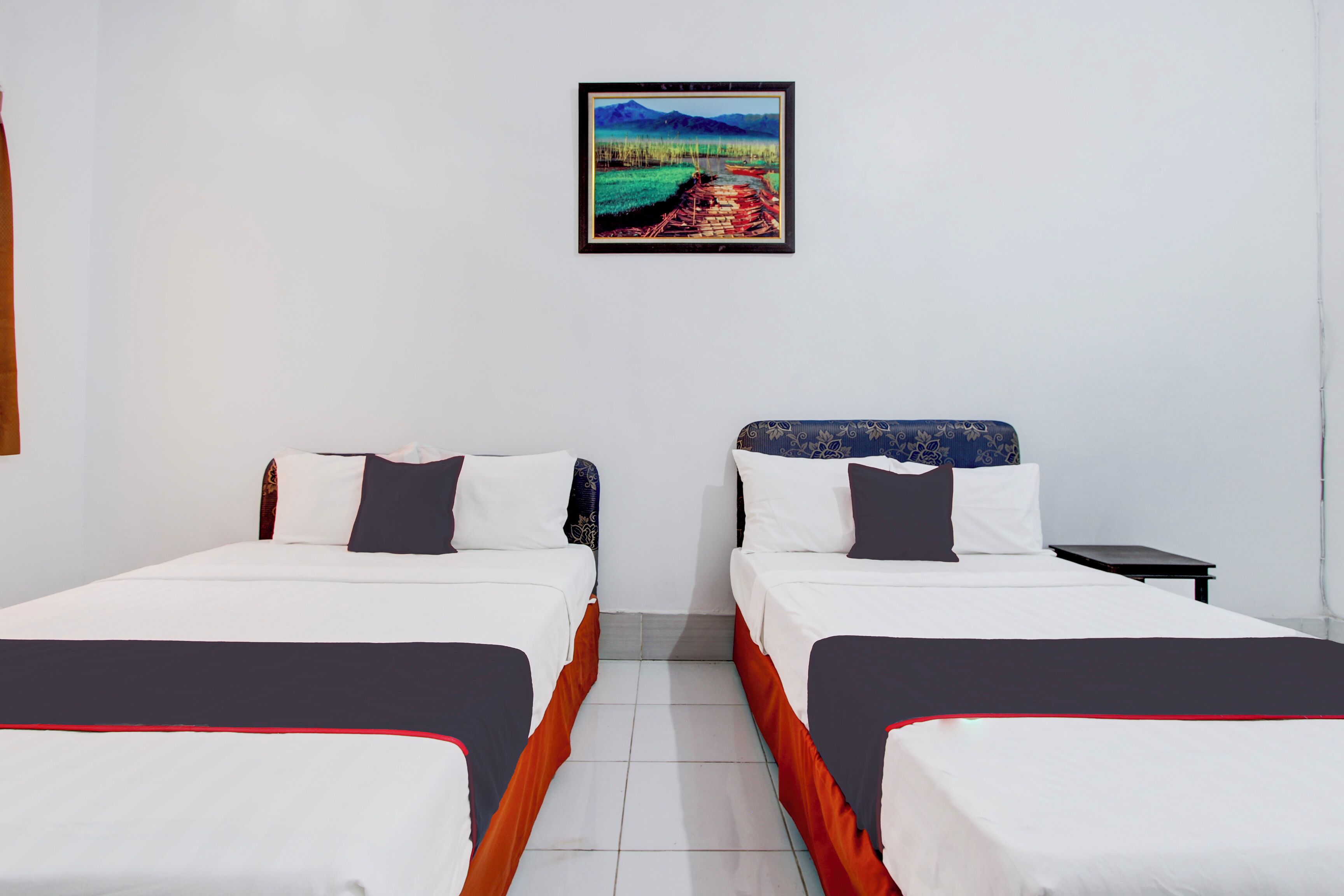 A hotel room with two beds, a small table, and a framed picture on the wall.