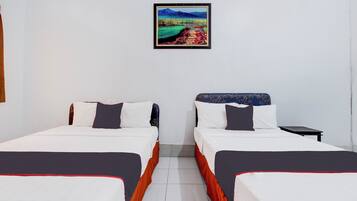 A hotel room with two beds, a small table, and a framed picture on the wall.