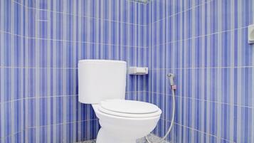A bathroom with a toilet, a wall-mounted bidet, and a patterned floor.