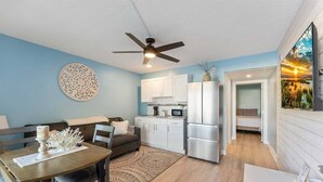 Un espacio habitable compacto con comedor, kitchenette y un dormitorio.