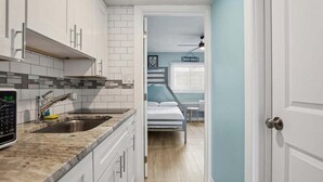 Une cuisine de taille réduite avec des meubles blancs, un plan de travail en granit et un évier.