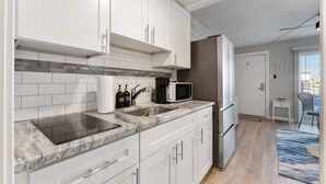 A modern kitchen with white cabinets, a built-in microwave, and a stainless steel sink.