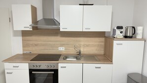 A compact kitchen with white cabinets, a stainless steel sink, a built-in oven, and a coffee maker on the countertop. - #3 Top room: central & comfortable, shared bathroom (Herne)