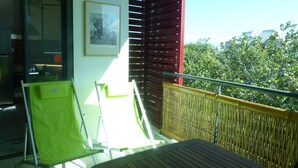 A balcony with a table, a chair, and a view of trees and buildings. - Attractive T2 apartment on the Saint Pierre waterfront in an ideally located building. (Saint-Pierre)